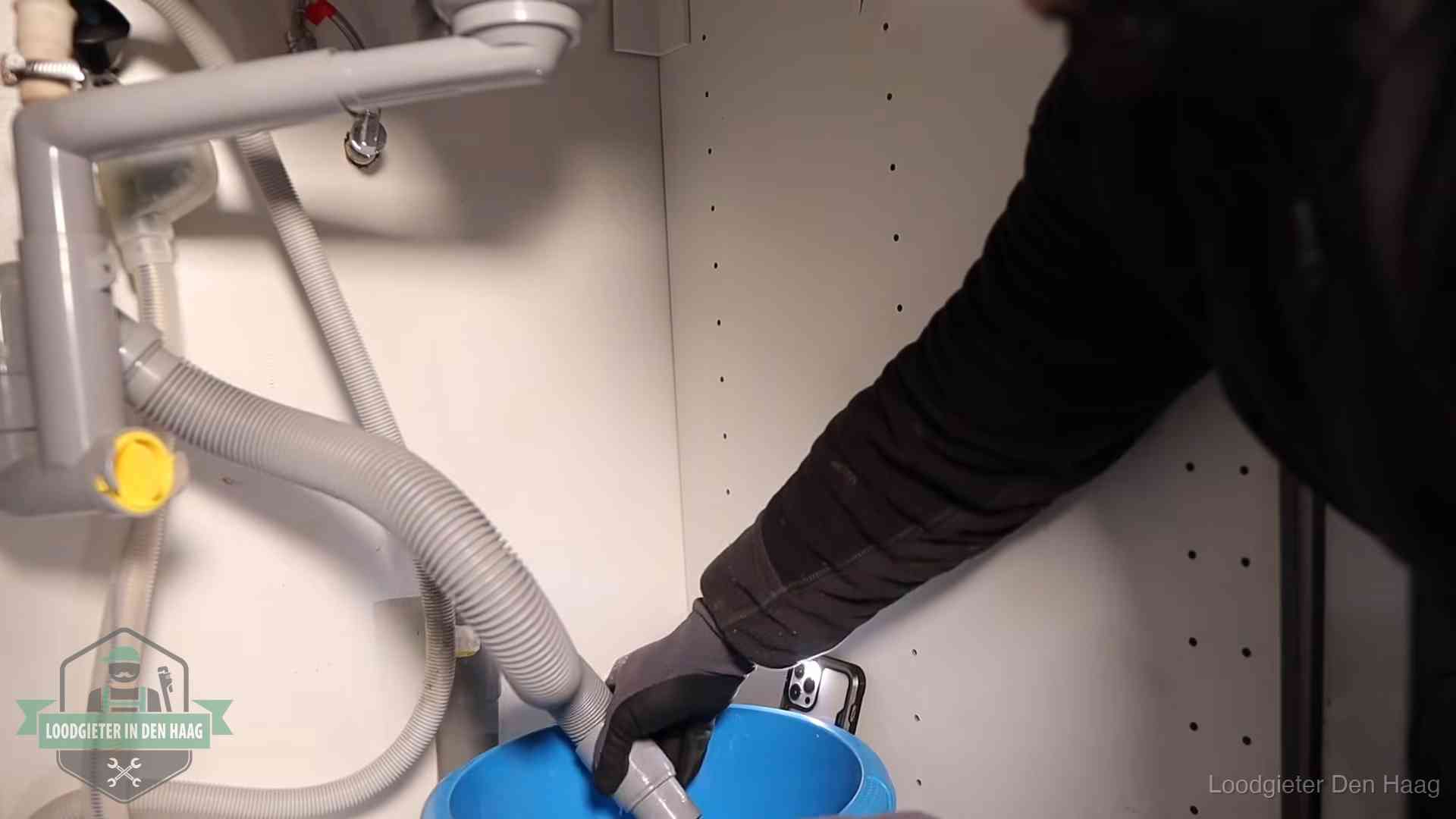 Afvoerslang loopt leeg in een emmer onder de gootsteen in Den Haag, een klus die je zelf kunt doen