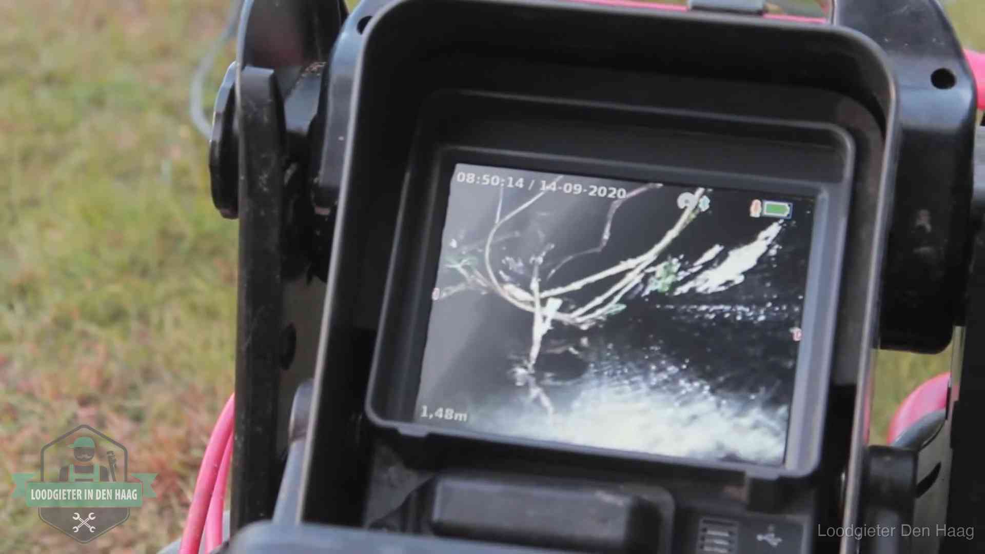 Monitor van een rioolcamera toont wortelingroei in de rioolbuis bij een woning in Den Haag