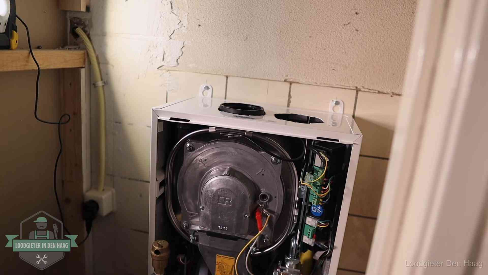 Geopende cv-ketel tijdens een onderhoudsbeurt in Den Haag, met brander en warmtewisselaar zichtbaar
