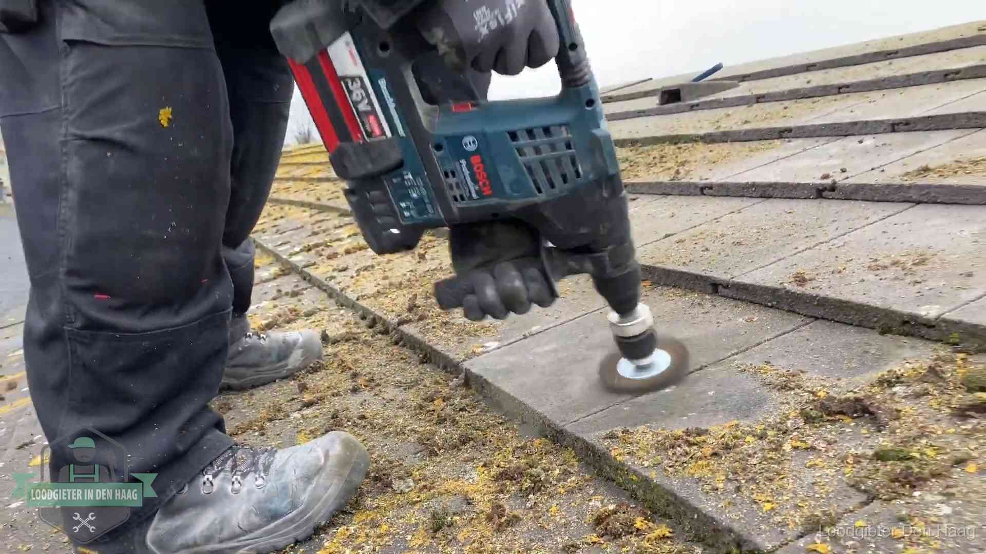 Betonnen dakpannen worden machinaal gereinigd tijdens dakonderhoud in Den Haag