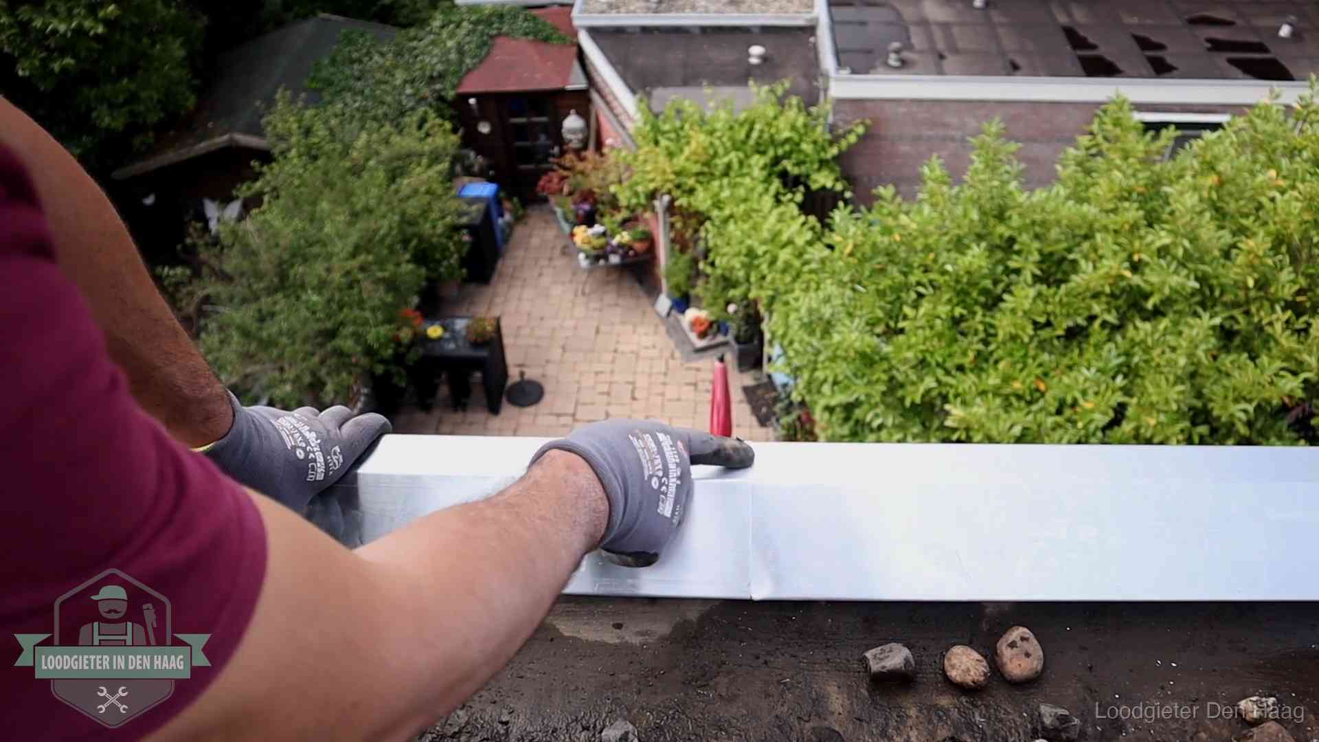 Vakman plaatst een daktrim op de dakrand van een woning in Den Haag
