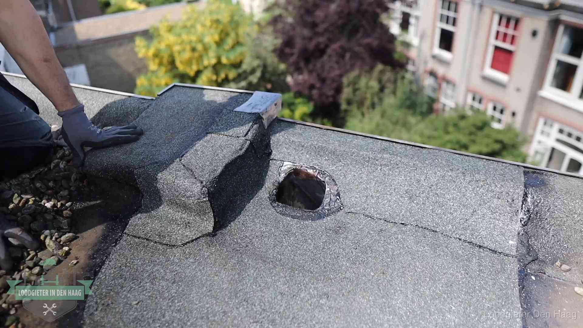 Loodgieter inspecteert een beschadigd bitumen plat dak tijdens een daklekkage-inspectie in Den Haag