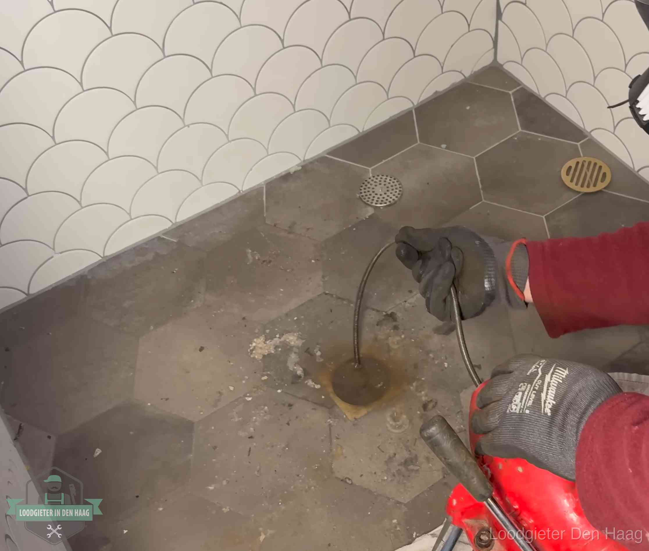 Ontstoppingsveer gaat in een geopend doucheputje in Den Haag waar het water omhoogkwam