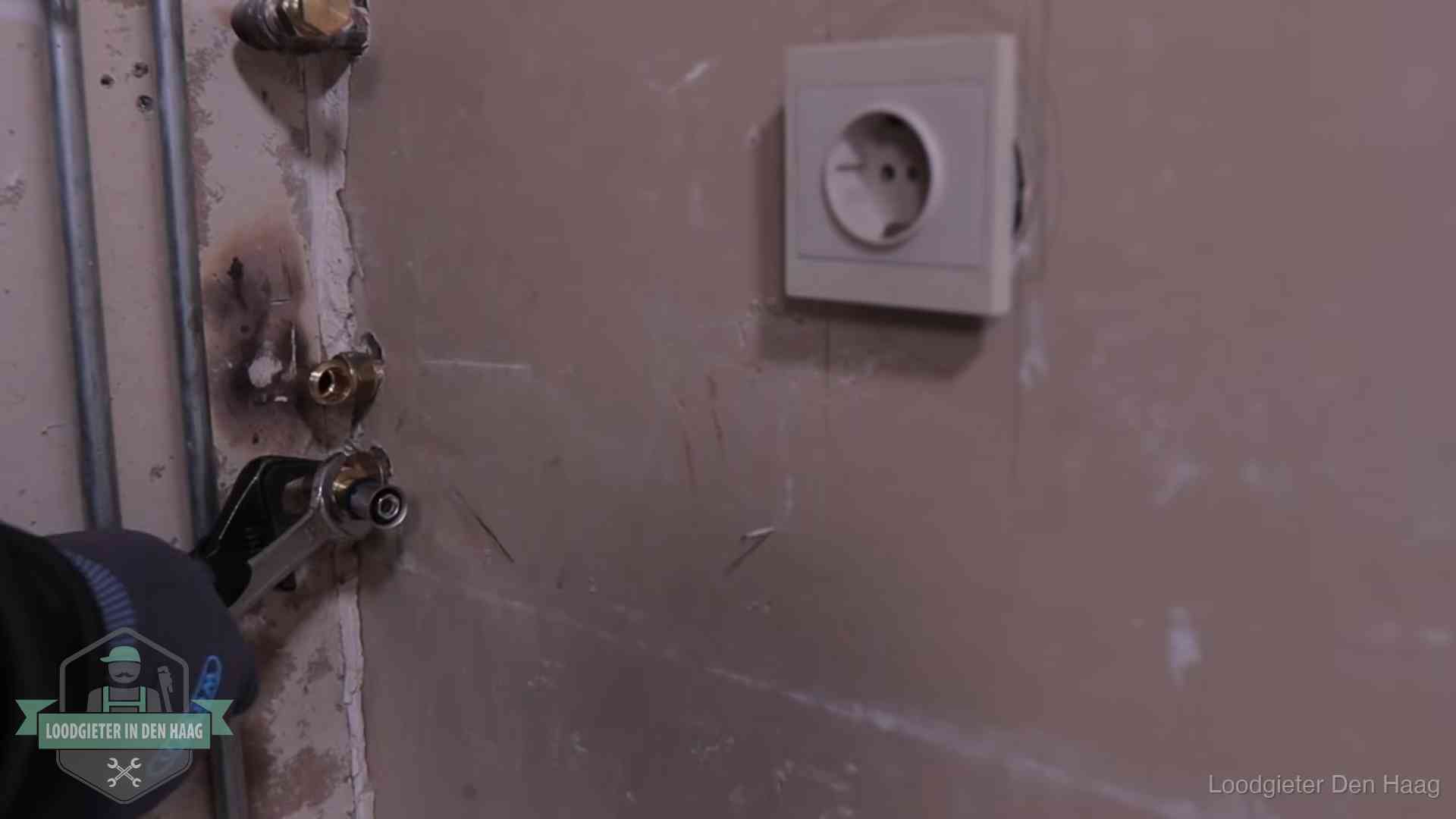 Monteur draait een perskoppeling vast op een leidingaansluiting in Den Haag