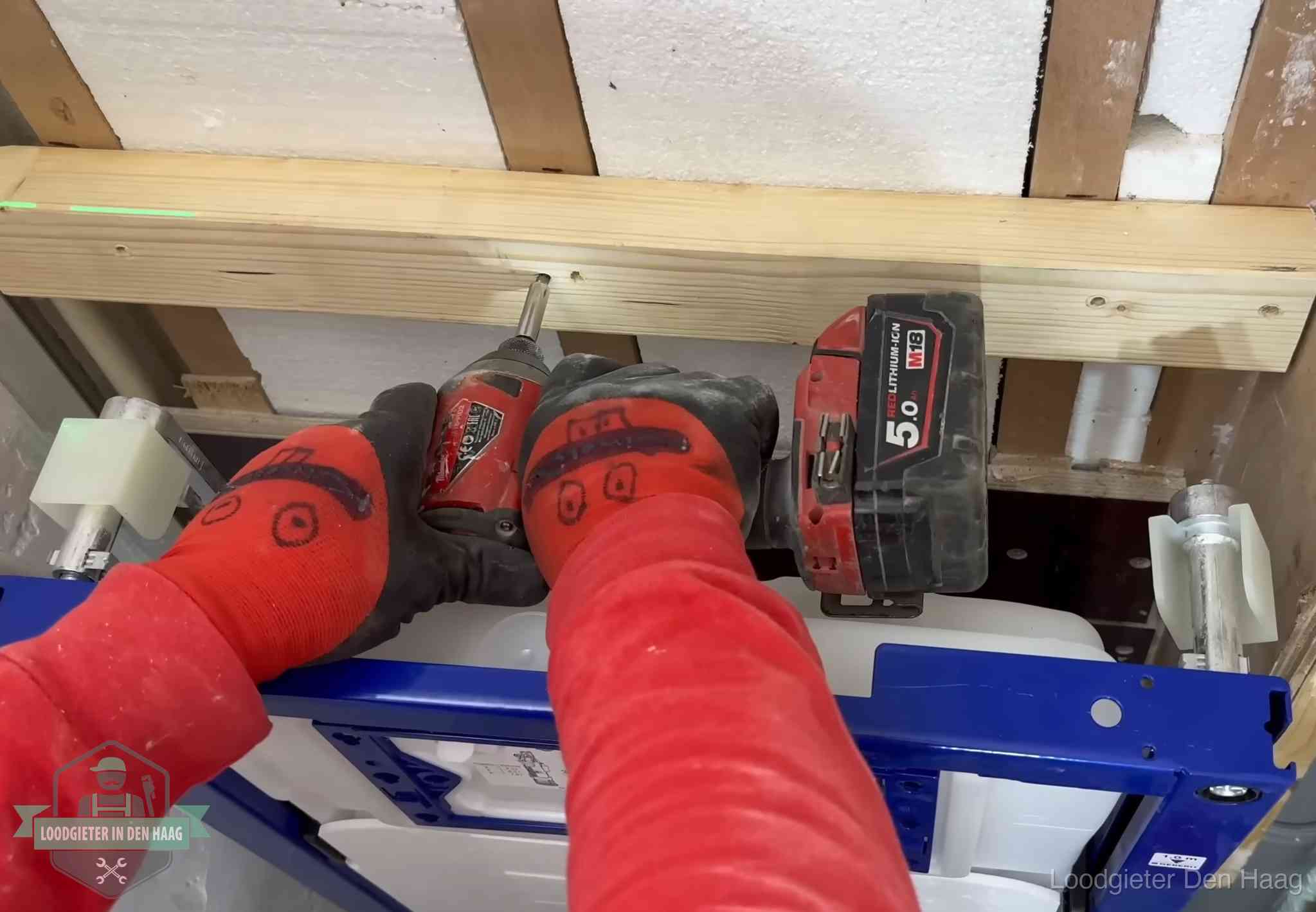 Monteur bevestigt een inbouwreservoir voor een hangend toilet in Den Haag