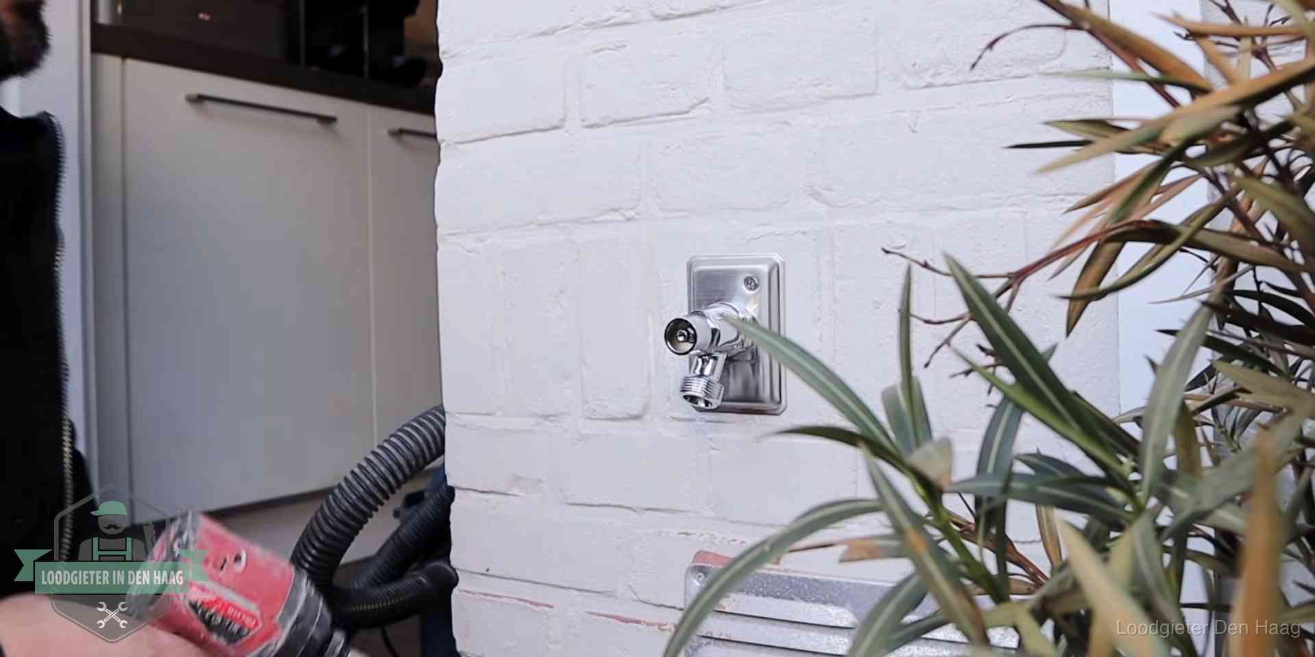 Chromen kraan op een muurplaat bij een woning in Den Haag, dichtdraaien is stap een van de lektest