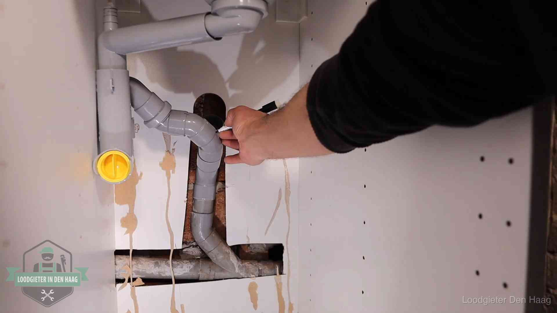 Loodgieter markeert een pvc-afvoerbuis onder een gootsteen in Den Haag