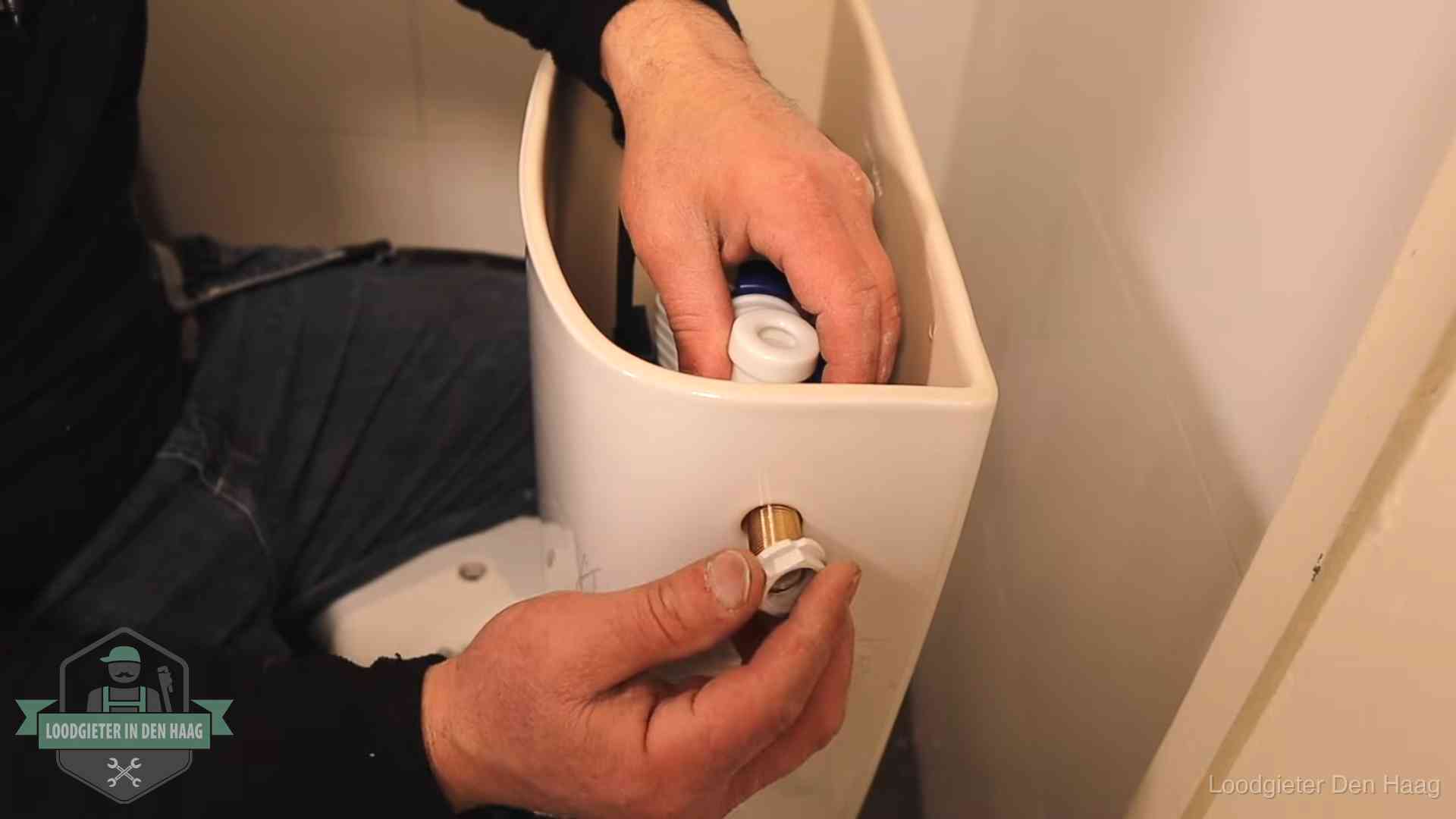 Loodgieter monteert de vlotterkraan van een stortbak bij een toilet in Den Haag