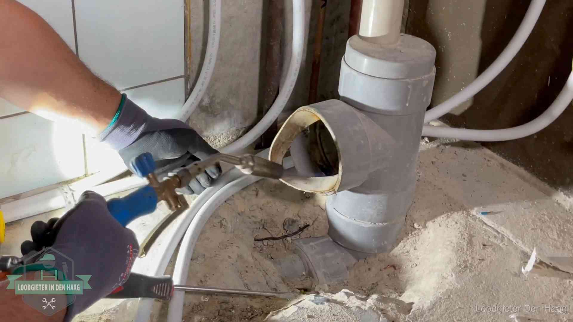 Loodgieter werkt met brander en messing kraanwerk aan leidingen in Den Haag