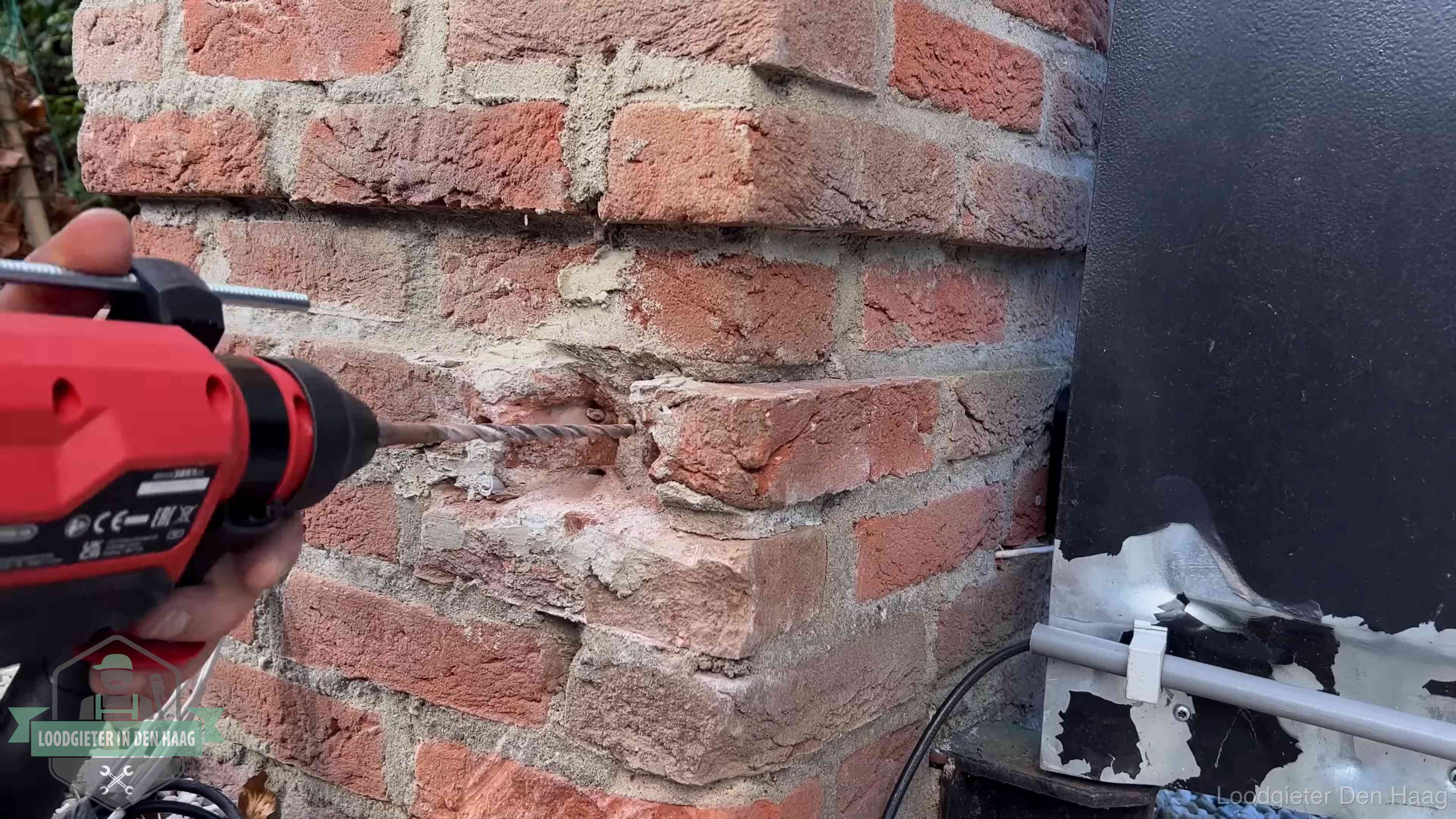 Vakman boort in de buitenmuur van een woning in de regio Den Haag