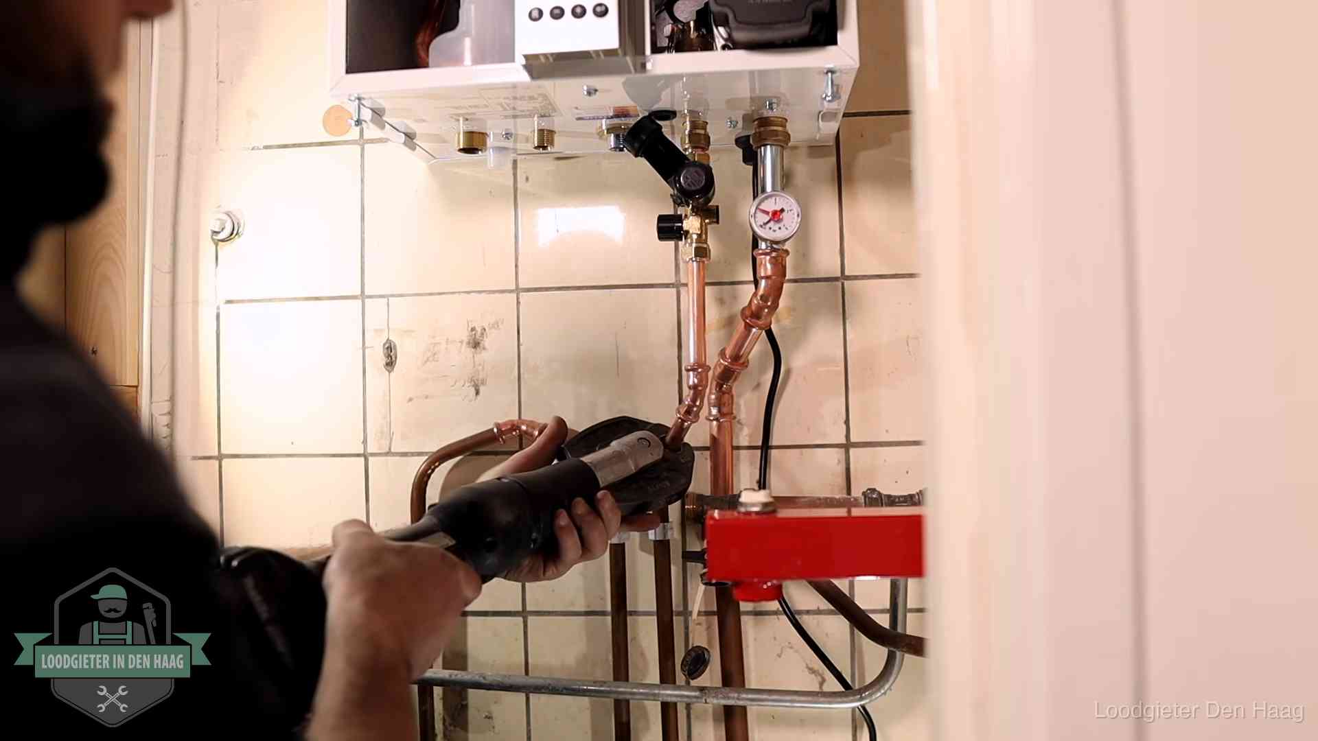 Monteur werkt aan de leidingen onder een cv-ketel in Den Haag