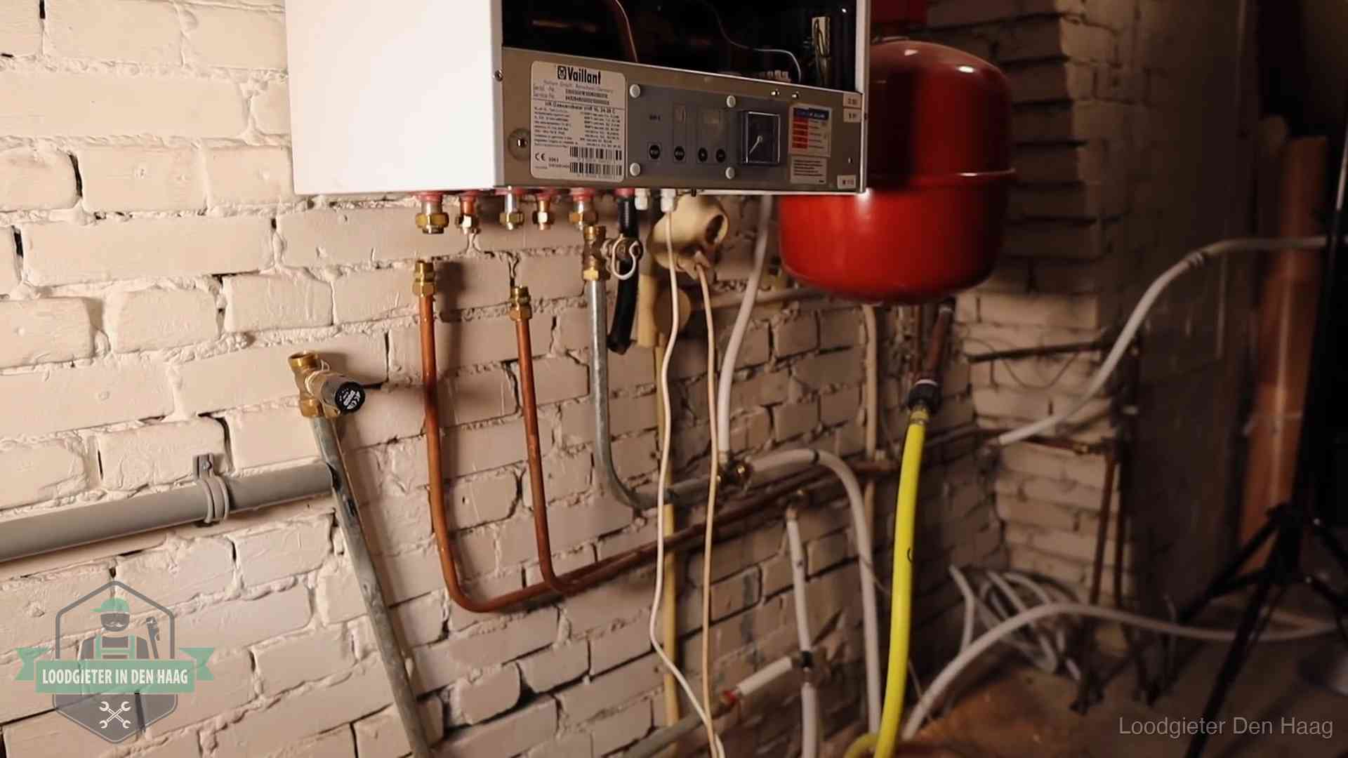 Verouderde cv-ketel met een wirwar van oude leidingen in een woning in Den Haag