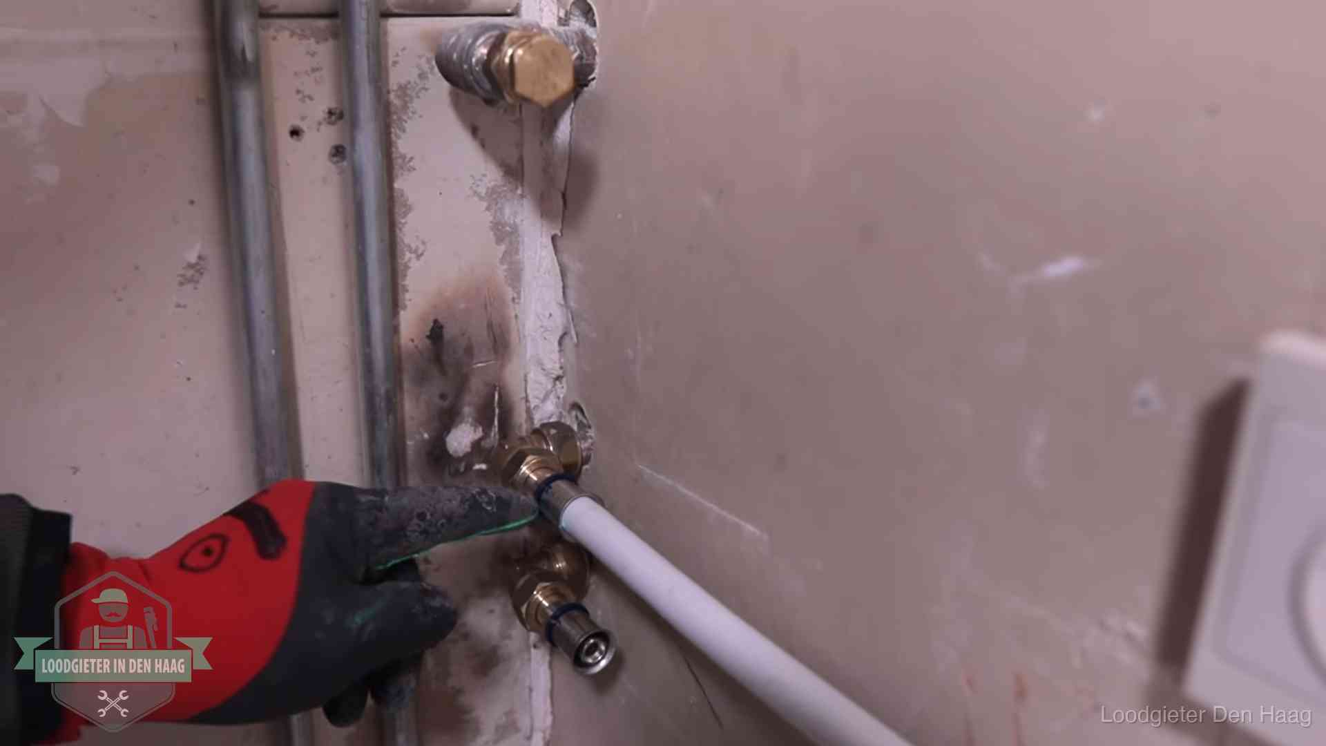 Loodgieter wijst de persfitting op nieuwe muuraansluitingen aan in een woning in Den Haag