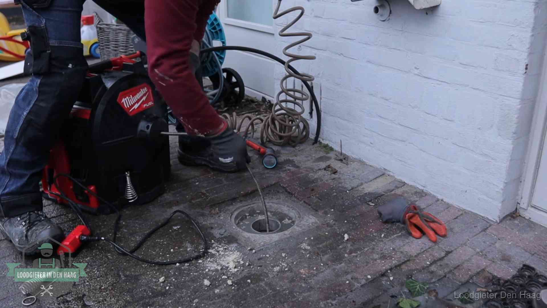 Spiraalmachine bij een ontstoppingsputje in de bestrating in Den Haag