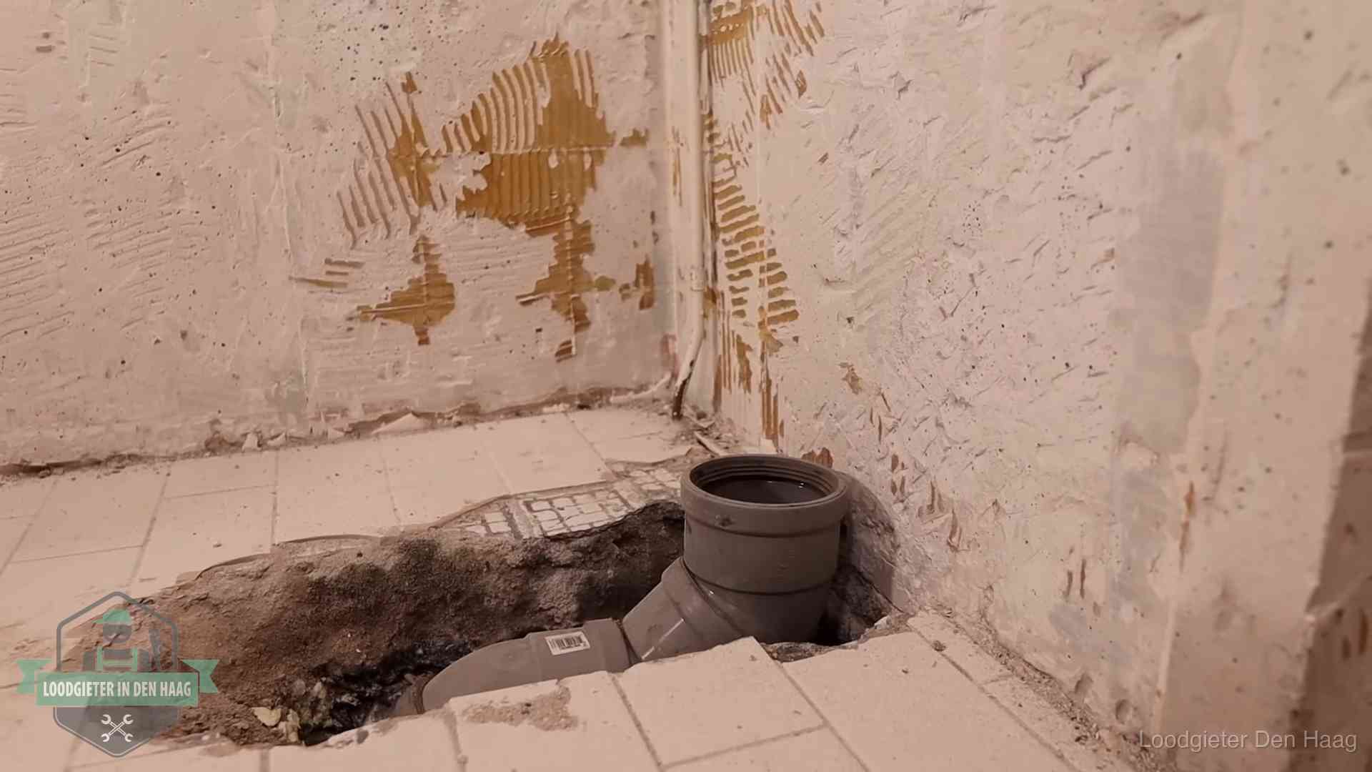Opengebroken vloer met een nieuwe pvc-rioolbocht in een gegraven sleuf in Den Haag