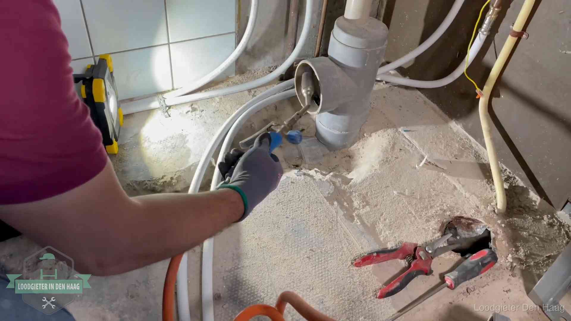 Loodgieter werkt aan leidingen bij een pvc-standleiding in een appartement in Den Haag