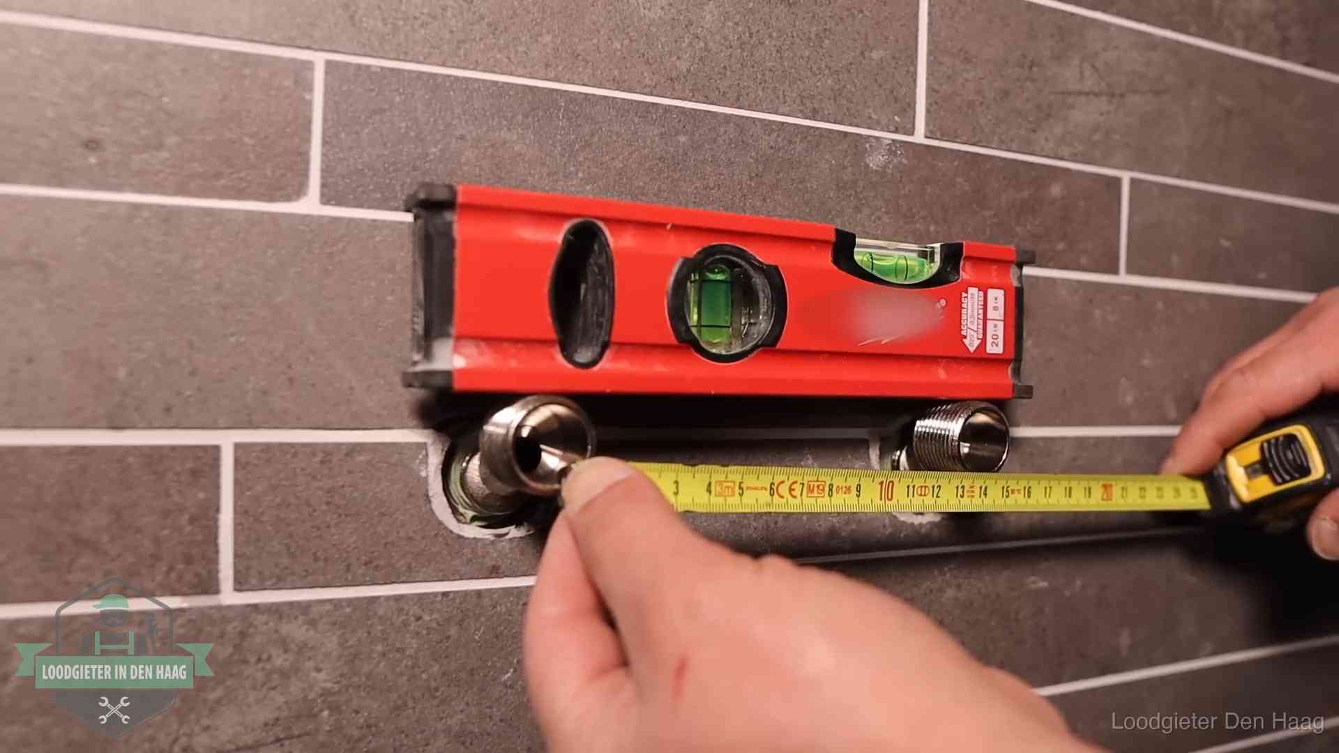 Waterpas en duimstok bij kraan-aansluitpunten in een badkamer in Den Haag