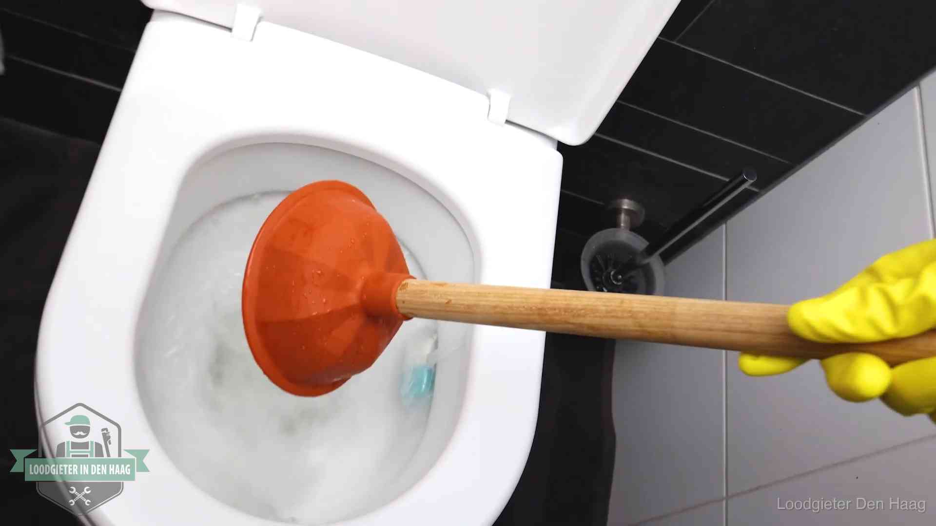Plopper wordt in de wc-pot gedrukt bij het ontstoppen van een toilet in Den Haag