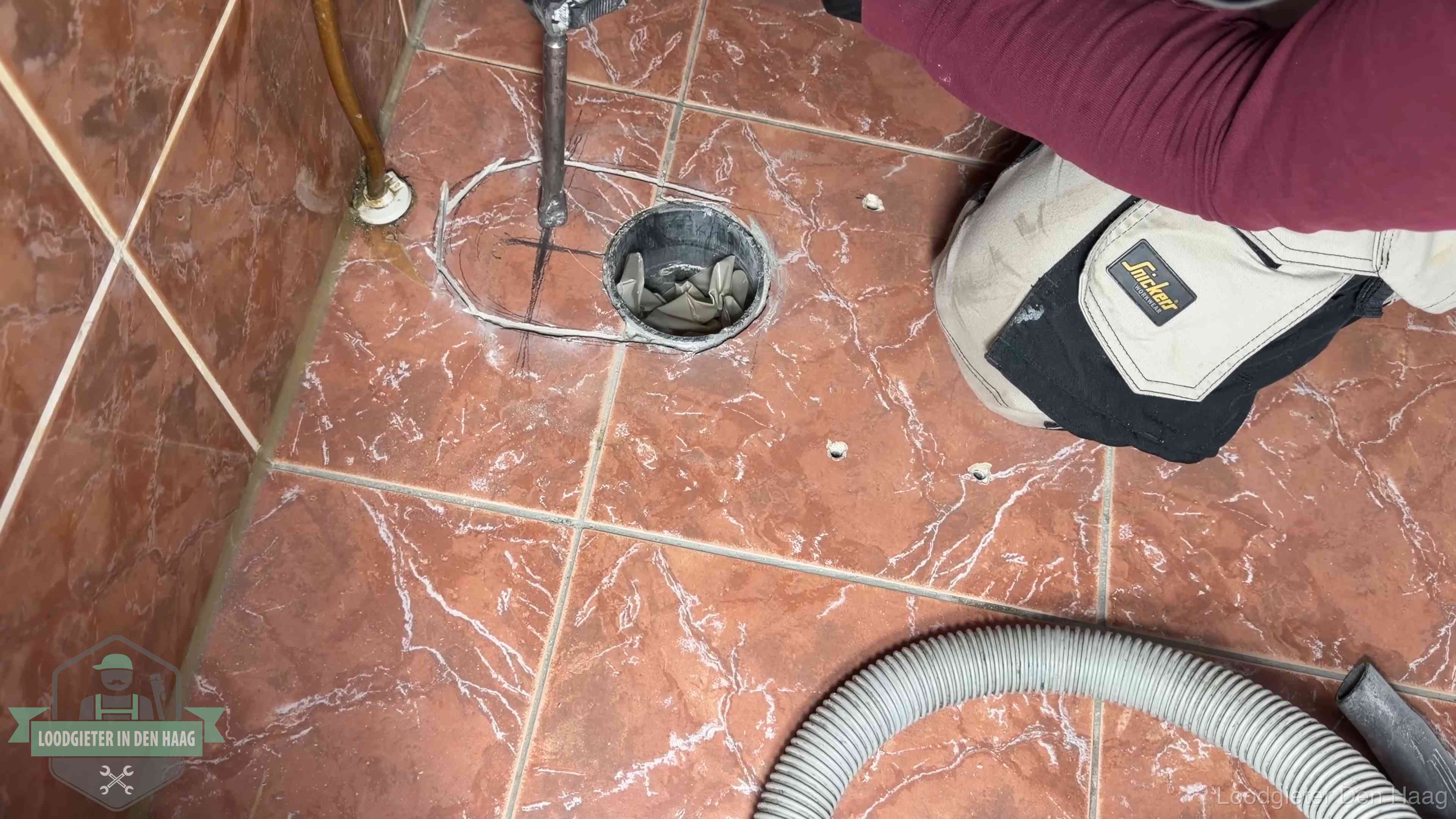 Open rioolaansluiting in de vloer waar de wc-pot is gedemonteerd in Den Haag