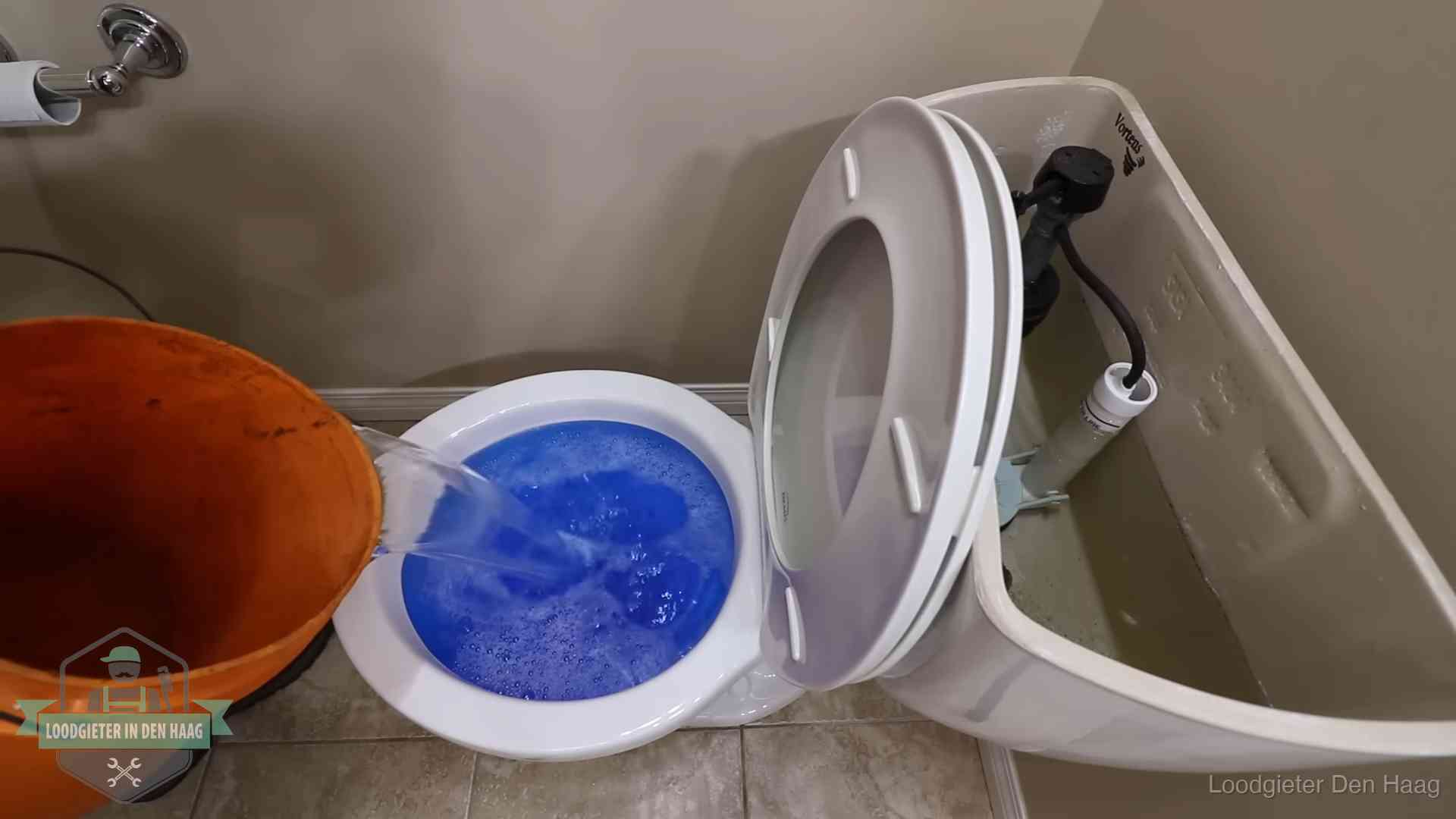 Water bij de wc-pot wordt met een emmer weggewerkt om schade te beperken in Den Haag